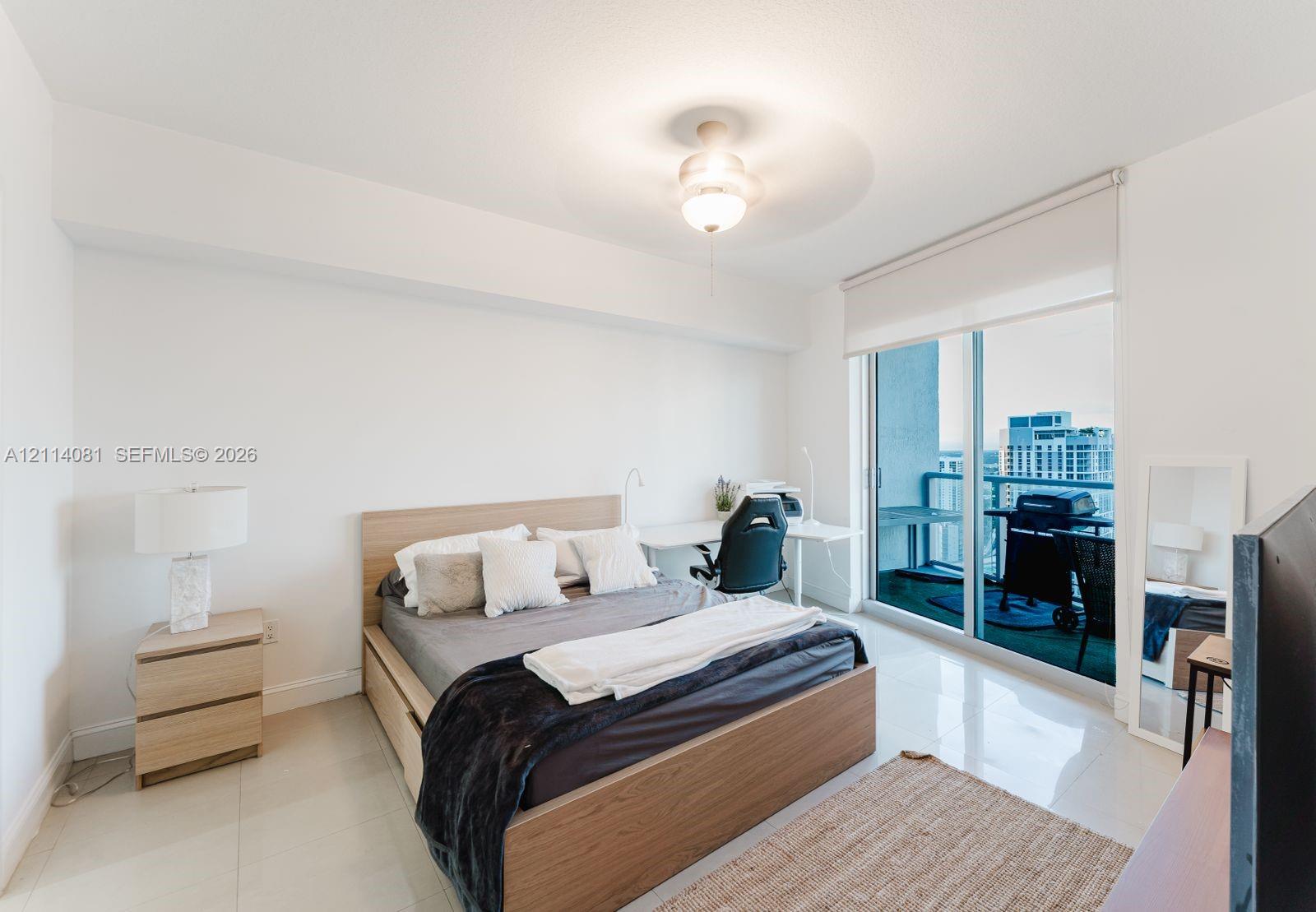 Polished tile flooring, neutral wall finishes, flush-mount ceiling lighting, and floor-to-ceiling glass sliding doors providing access to a private balcony