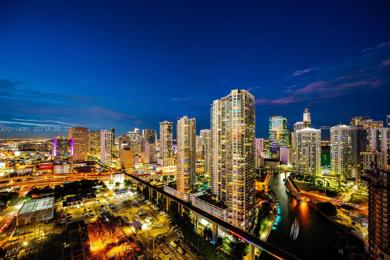 High-rise perspective featuring panoramic urban skyline, waterway, and illuminated infrastructure