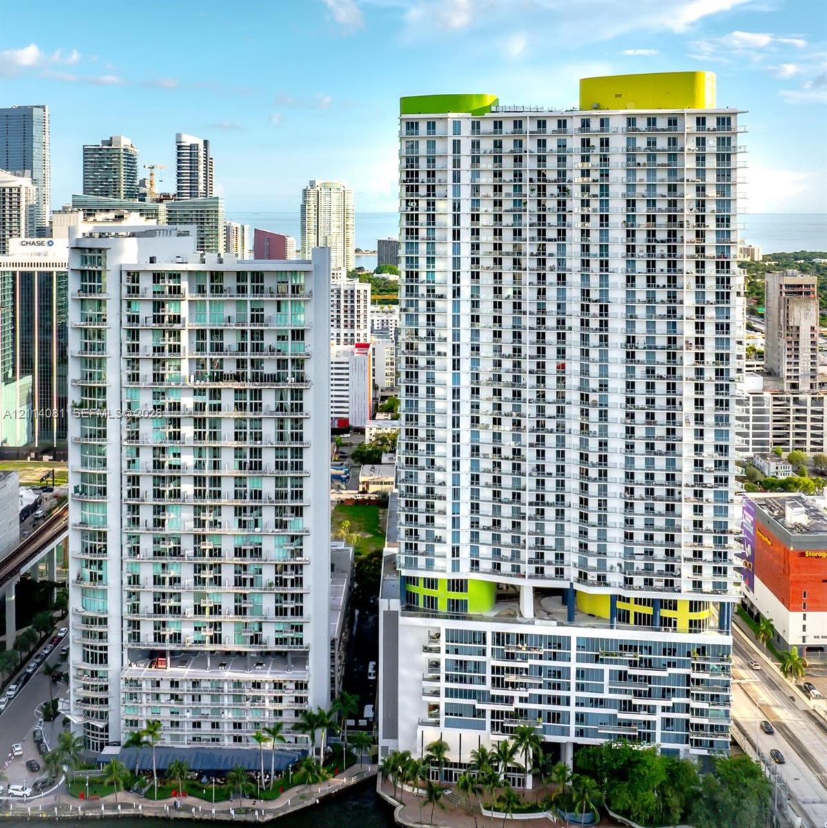 High-rise concrete structure featuring extensive glass balconies, floor-to-ceiling windows, and integrated rooftop architectural elements