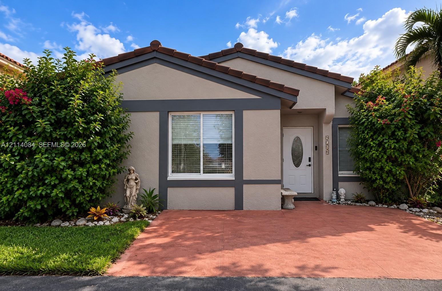 Single-story residence featuring a tile roof, stucco exterior with contrasting trim, and a paved front patio Single-story residence featuring a tile roof, stucco exterior with contrasting trim, and a paved front patio
