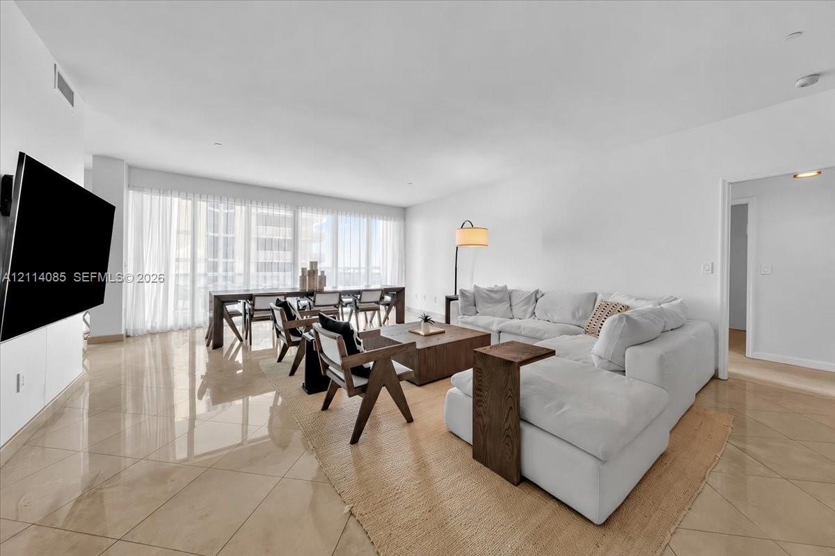 Open-concept room with large-format tile flooring, floor-to-ceiling windows, and recessed lighting