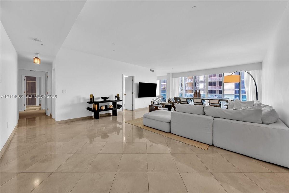 Large-format tile flooring, recessed ceiling lighting, and floor-to-ceiling windows featuring exterior building architecture