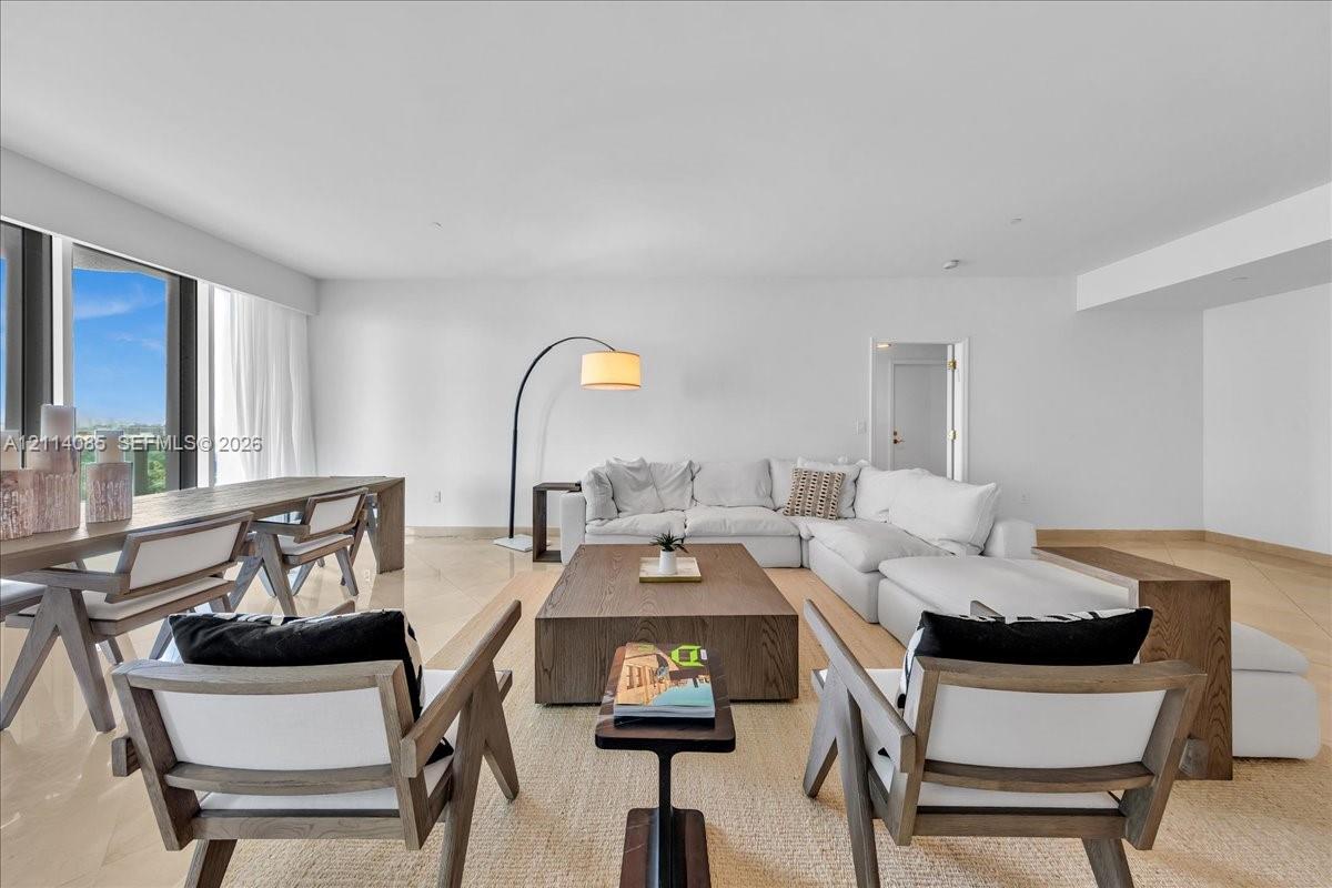 Open-concept interior featuring large-format stone flooring, expansive floor-to-ceiling windows, and neutral-toned wall finishes
