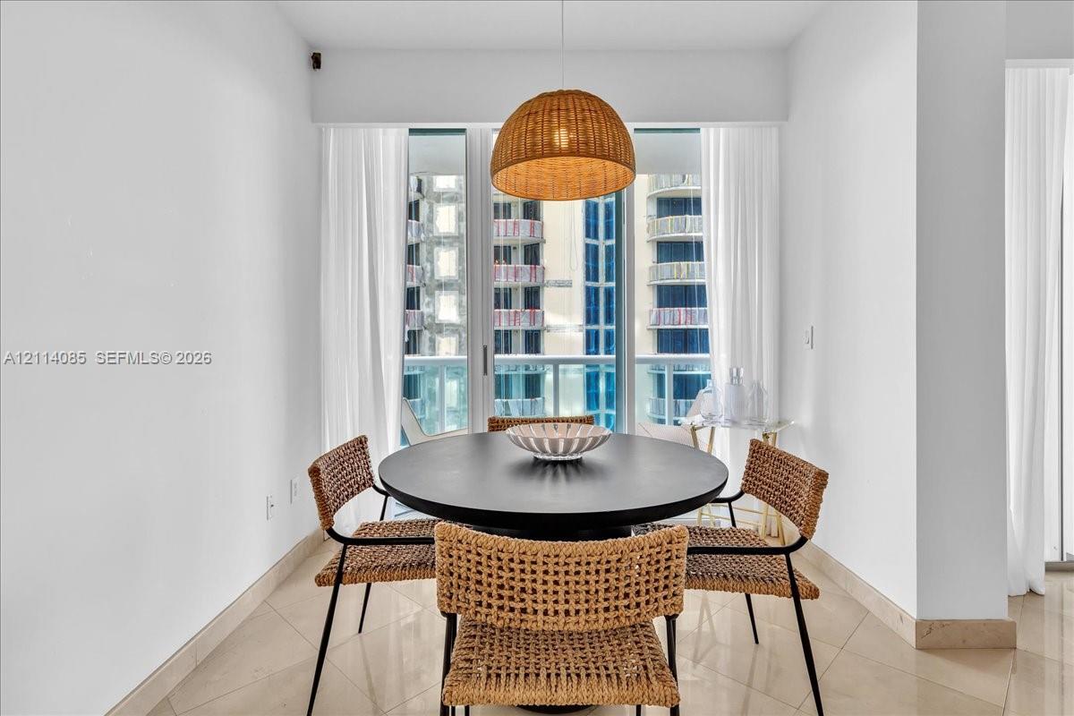 Floor-to-ceiling glass sliding doors, stone-finish flooring, and a textured pendant light fixture