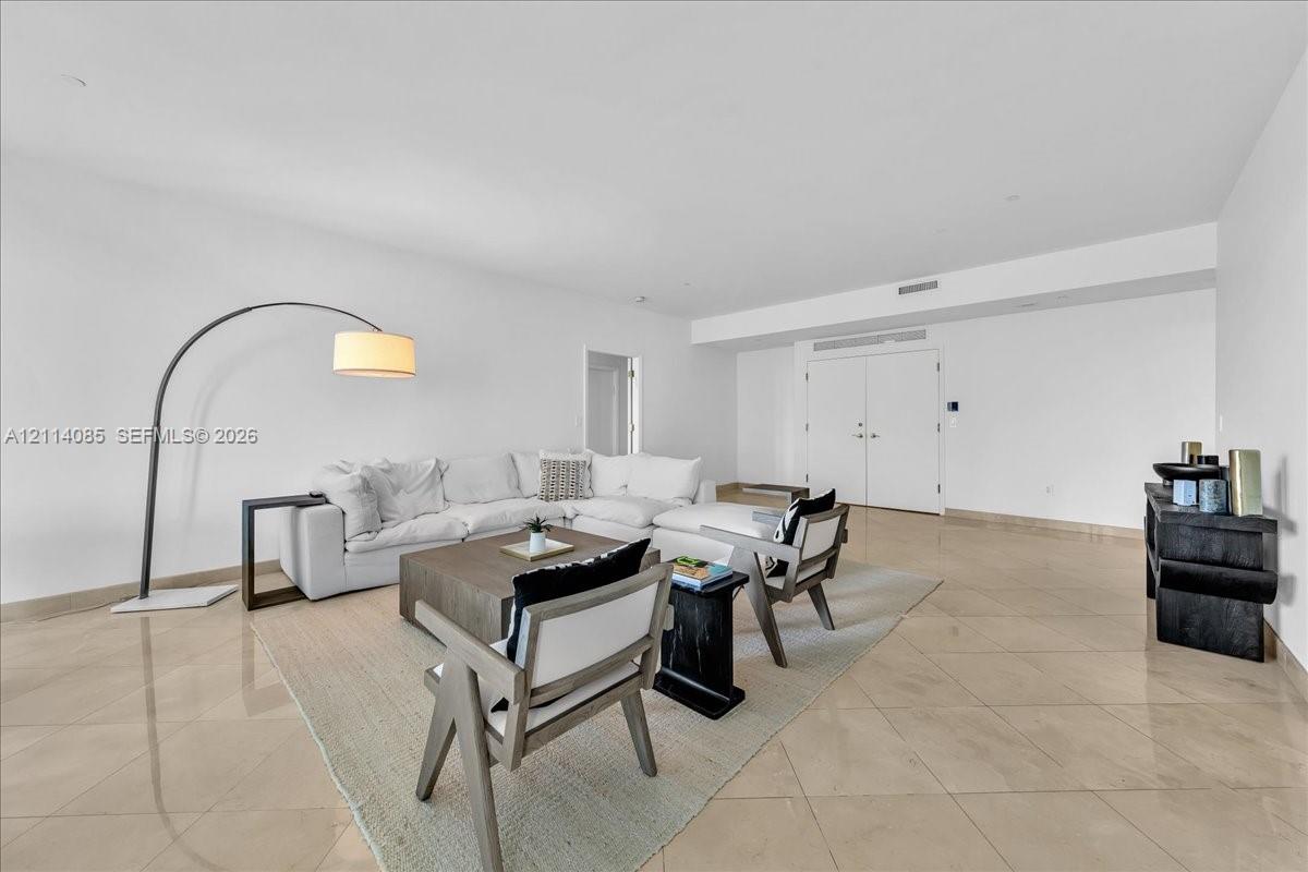 Spacious interior featuring large-format tile flooring, recessed ceiling lighting, and double-entry doors