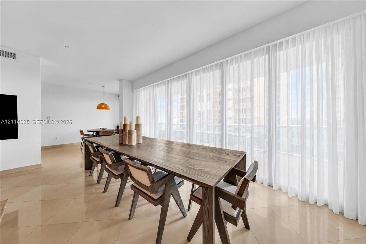 Open-concept interior featuring large-format tile flooring, recessed lighting, and a continuous wall of floor-to-ceiling windows