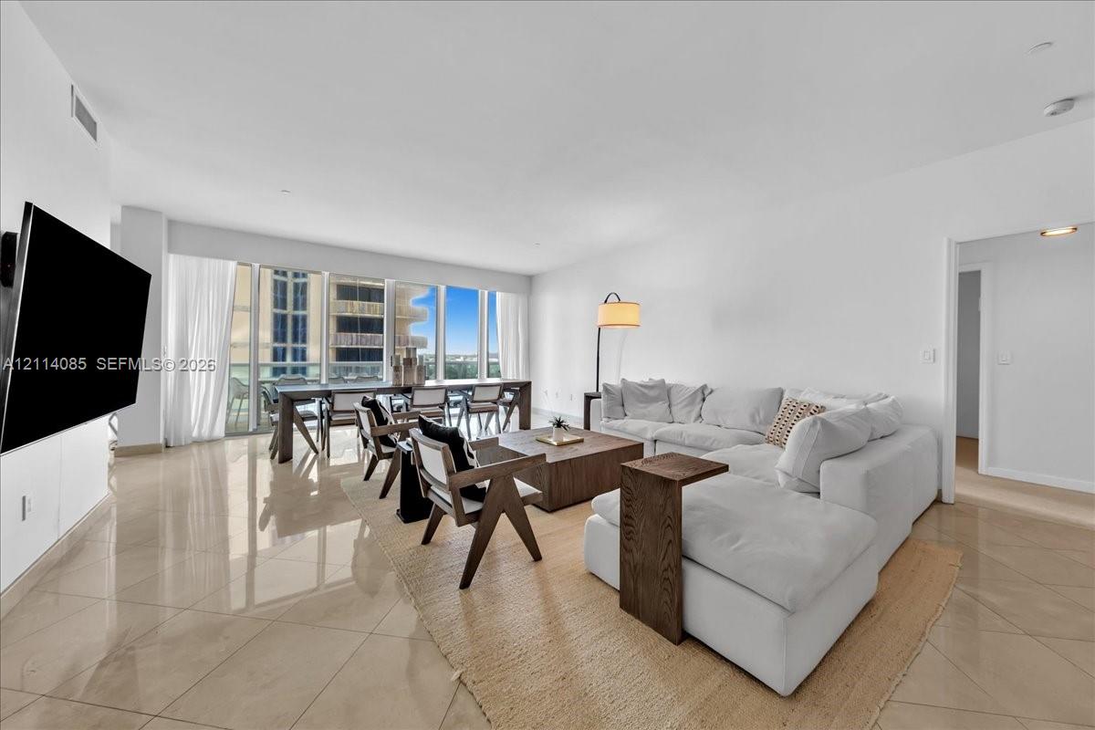 Open-concept living area featuring polished tile flooring, floor-to-ceiling windows, and recessed lighting