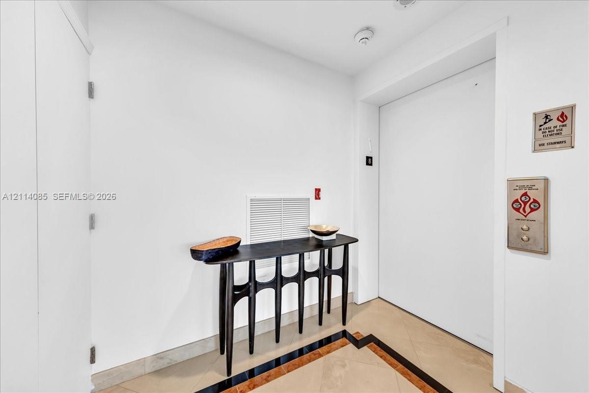 Elevator landing featuring stone flooring with inlaid border detail and direct elevator access