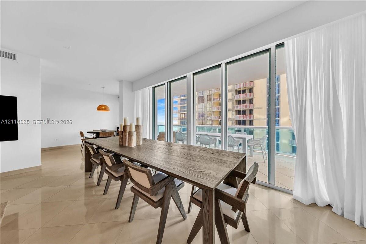 Floor-to-ceiling sliding glass doors, neutral tile flooring, and a covered balcony