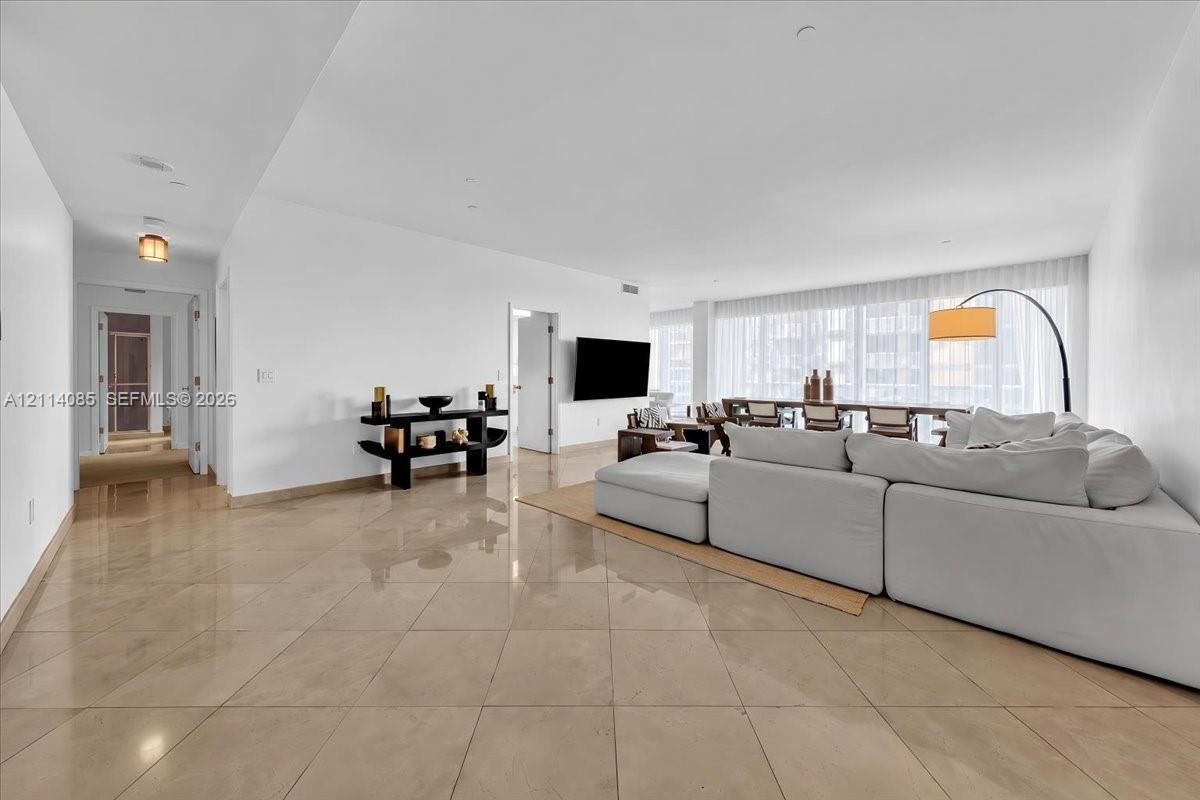 Large-format tile flooring, recessed ceiling lighting, and floor-to-ceiling windows with integrated drapery tracks