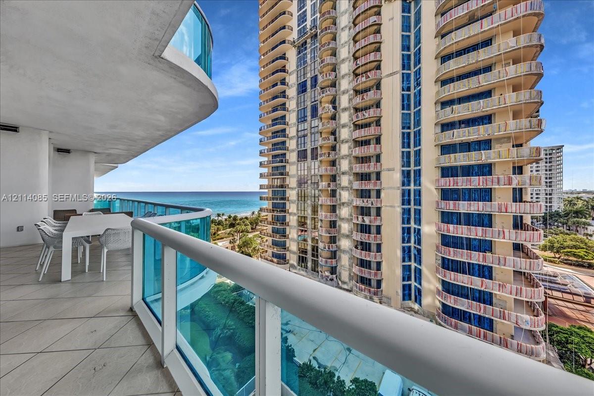 Curved private balcony featuring large-format tile flooring and blue glass panel railings