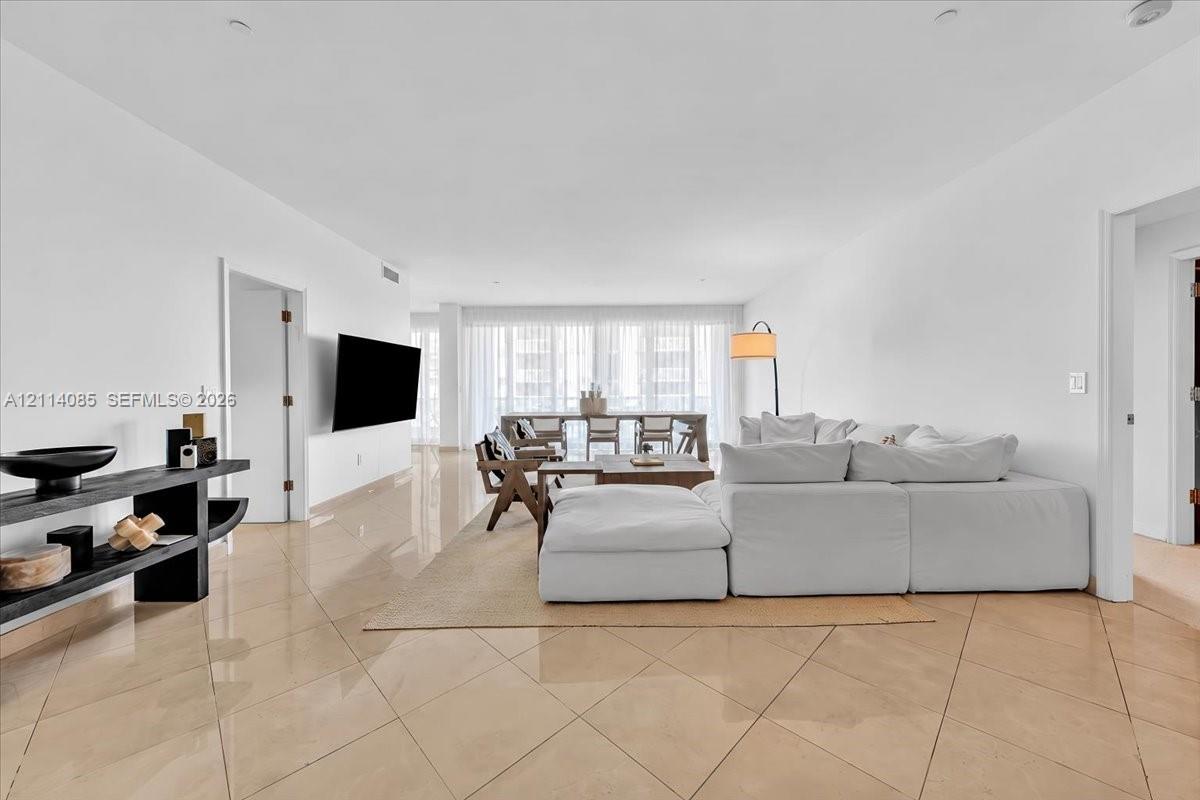 Open-concept living space featuring high-gloss tile flooring, recessed ceiling lighting, and expansive floor-to-ceiling windows