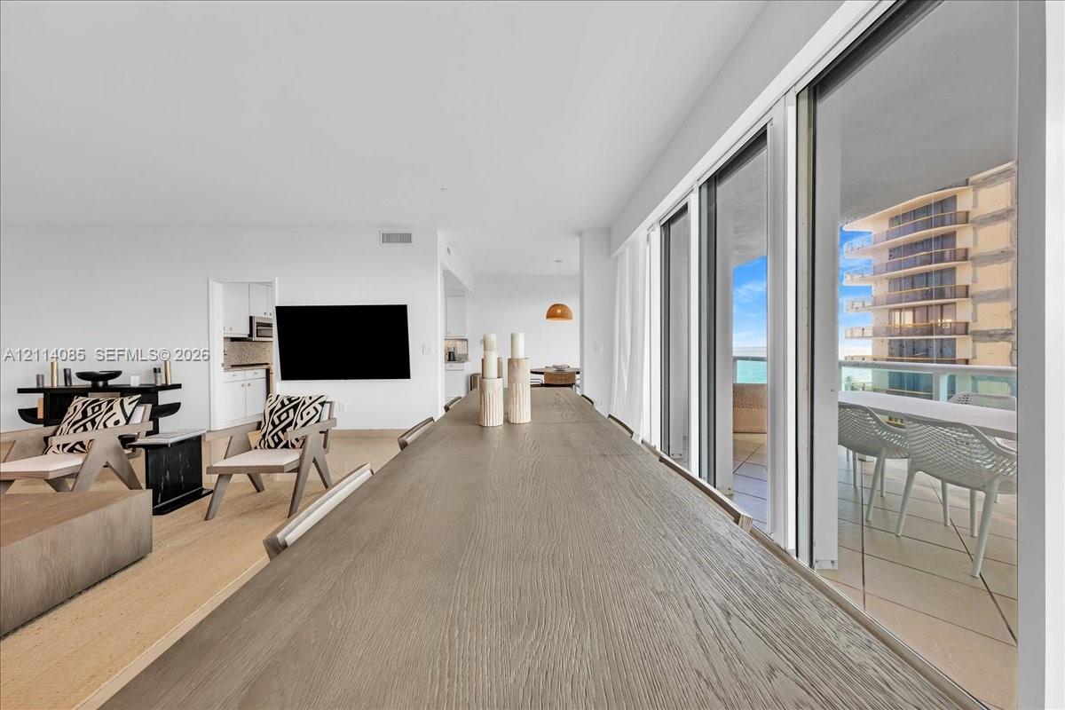 Open-concept floor plan featuring wood-finish flooring, sliding glass door panels, and a balcony with a glass railing