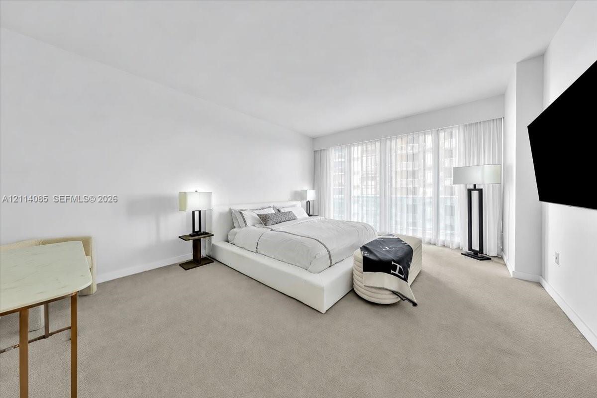 Expansive room featuring wall-to-wall carpeting, high ceilings, and floor-to-ceiling windows with full-length window treatments