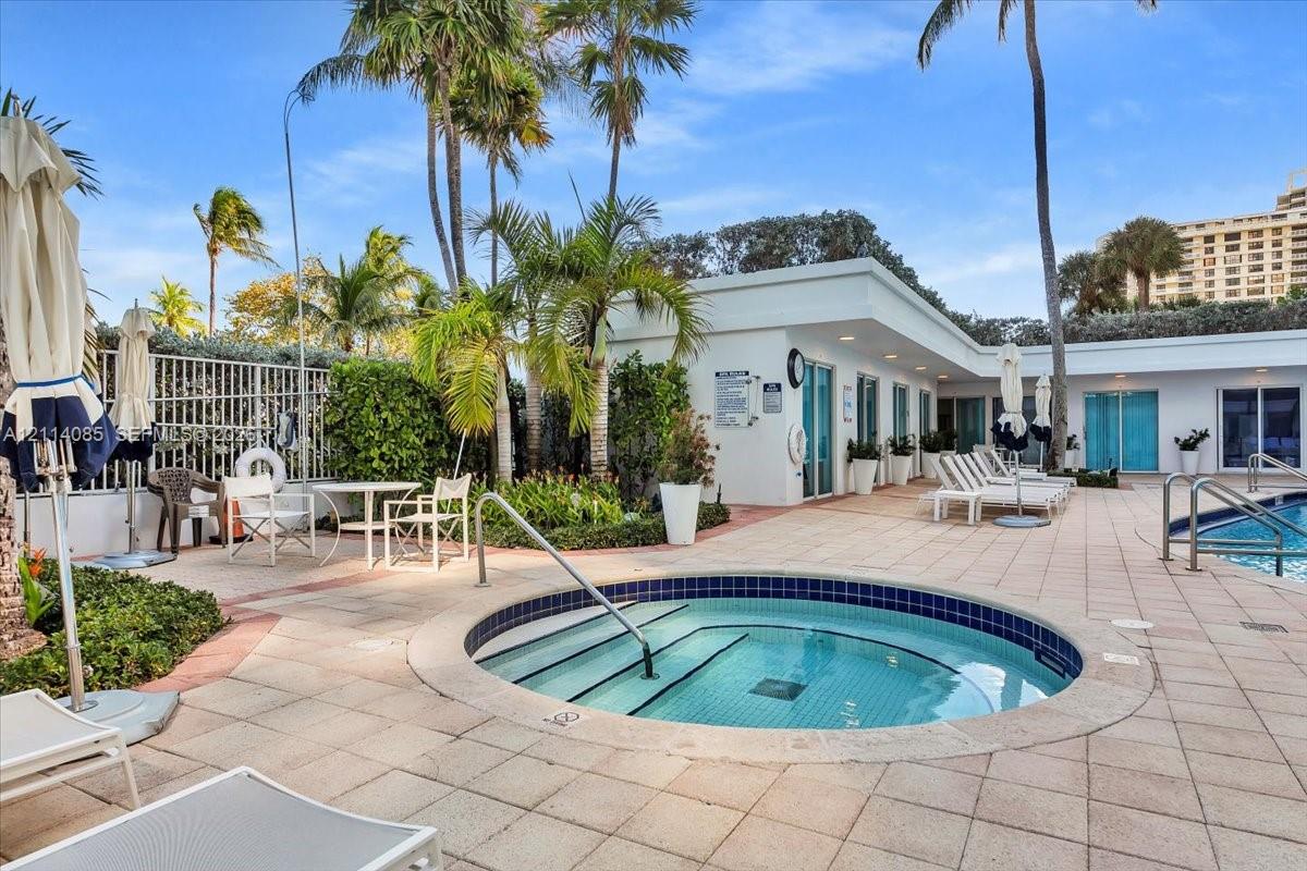 In-ground spa with tile surround, extensive paver patio, integrated swimming pool, and mature landscaping