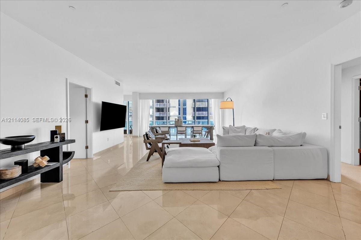 Open-concept floor plan with polished tile flooring, recessed lighting, and floor-to-ceiling windows