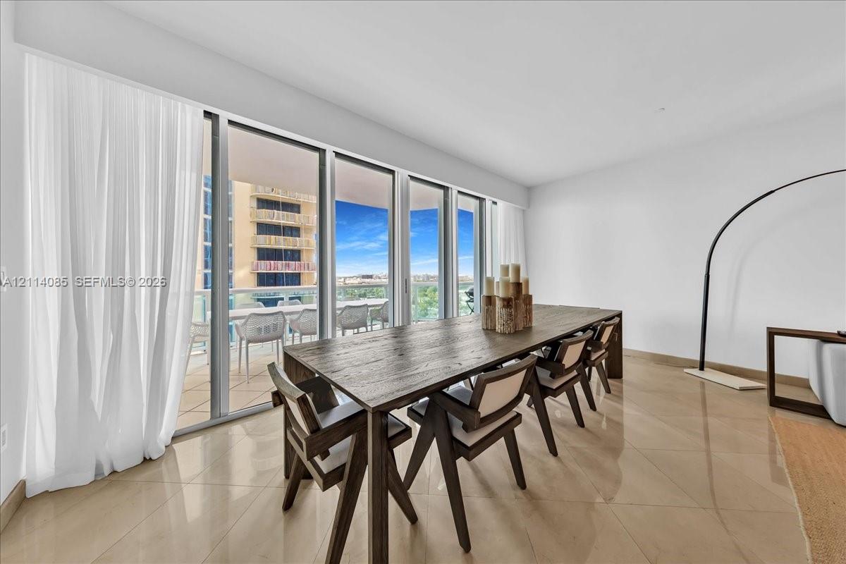Floor-to-ceiling glass sliding doors, private balcony with glass railing, large-format tile flooring, and neutral wall finishes
