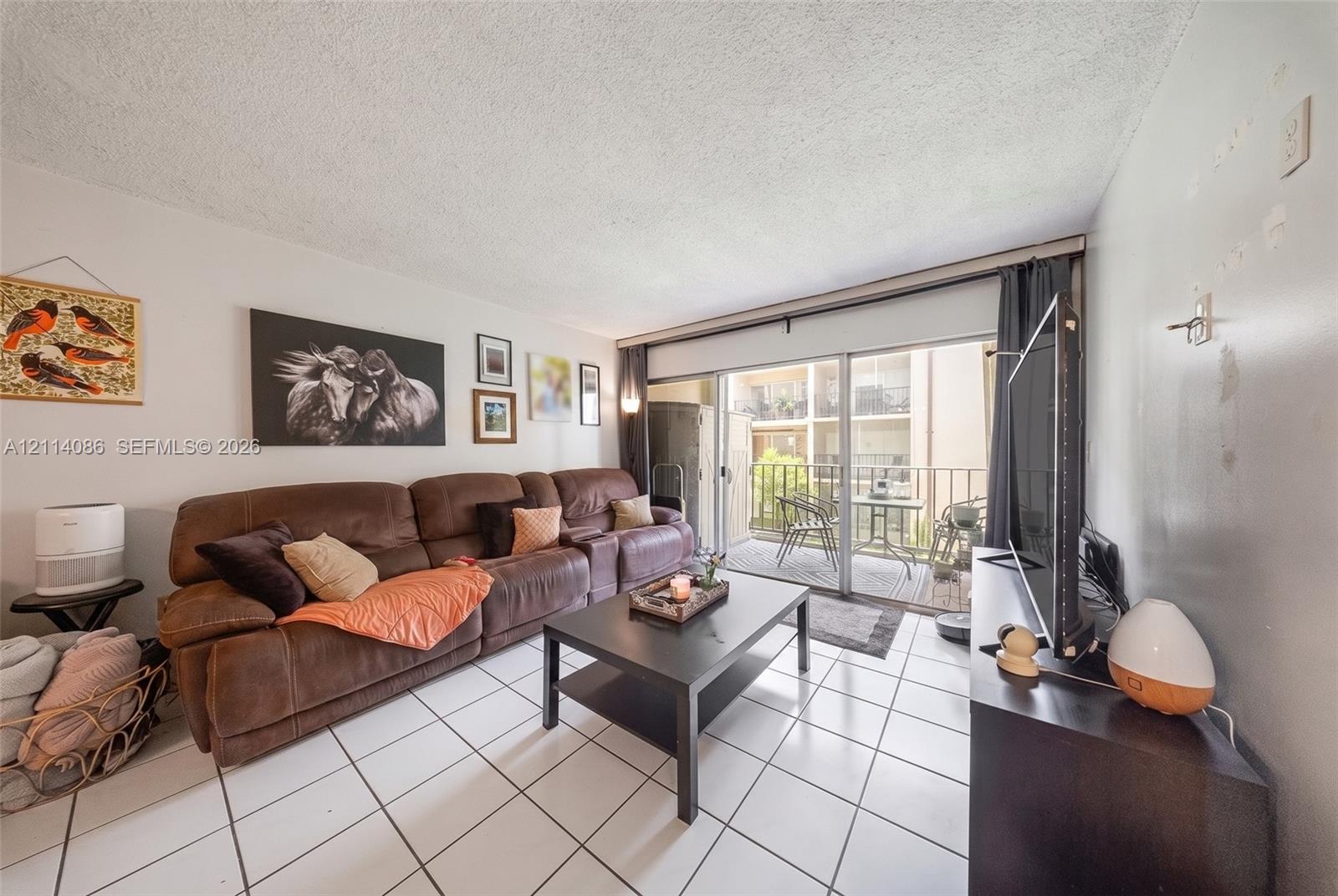 Living area featuring ceramic tile flooring and floor-to-ceiling sliding glass doors providing access to a private balcony