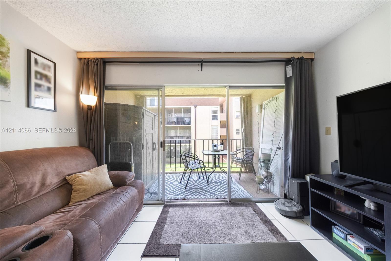 Sliding glass doors opening to a private balcony with metal railing and tile flooring