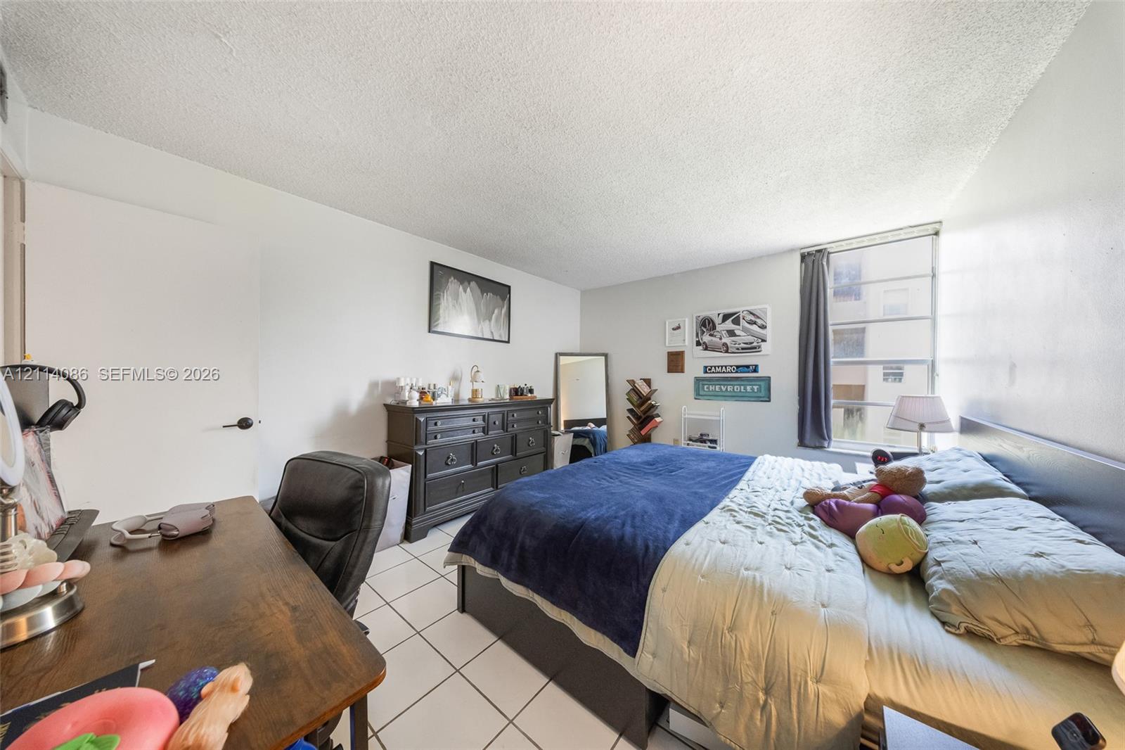 Bedroom featuring white tile flooring, neutral walls, and a large multi-pane window