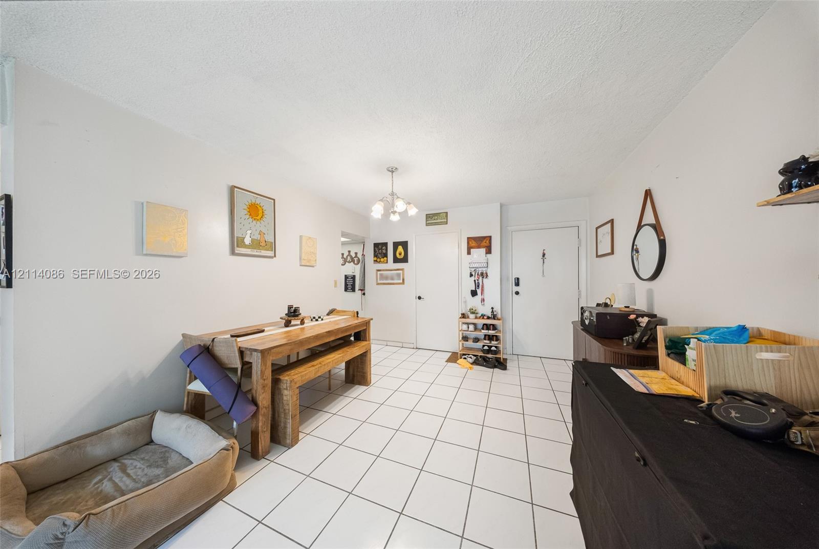 Neutral-tone interior featuring white ceramic tile flooring and a multi-arm chandelier