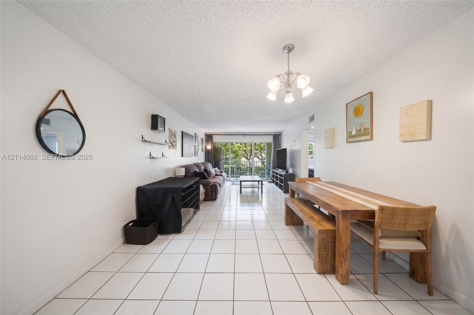 Open-concept living space featuring large-format tile flooring, a multi-arm ceiling-mounted light fixture, and floor-to-ceiling glass sliding doors