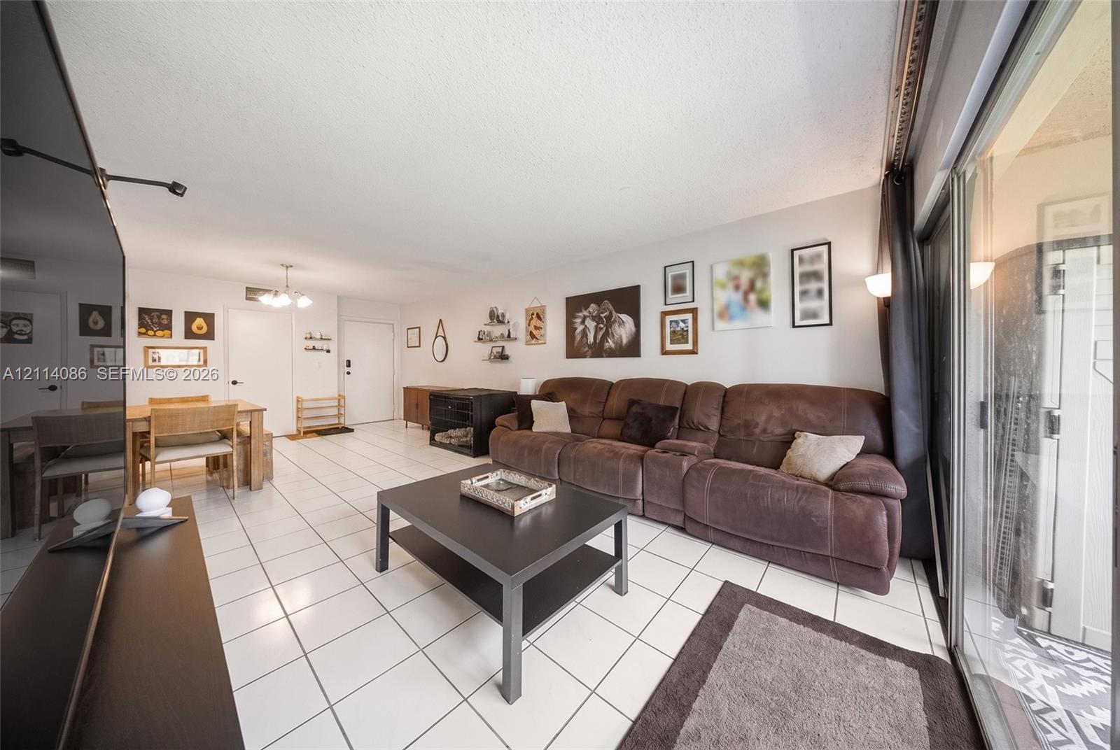 Open-concept interior featuring large-format ceramic tile flooring, sliding glass patio doors, and a multi-arm ceiling light fixture