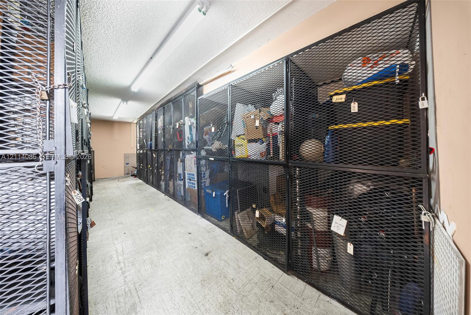 Dedicated storage room featuring floor-to-ceiling metal mesh enclosures and linear fluorescent lighting
