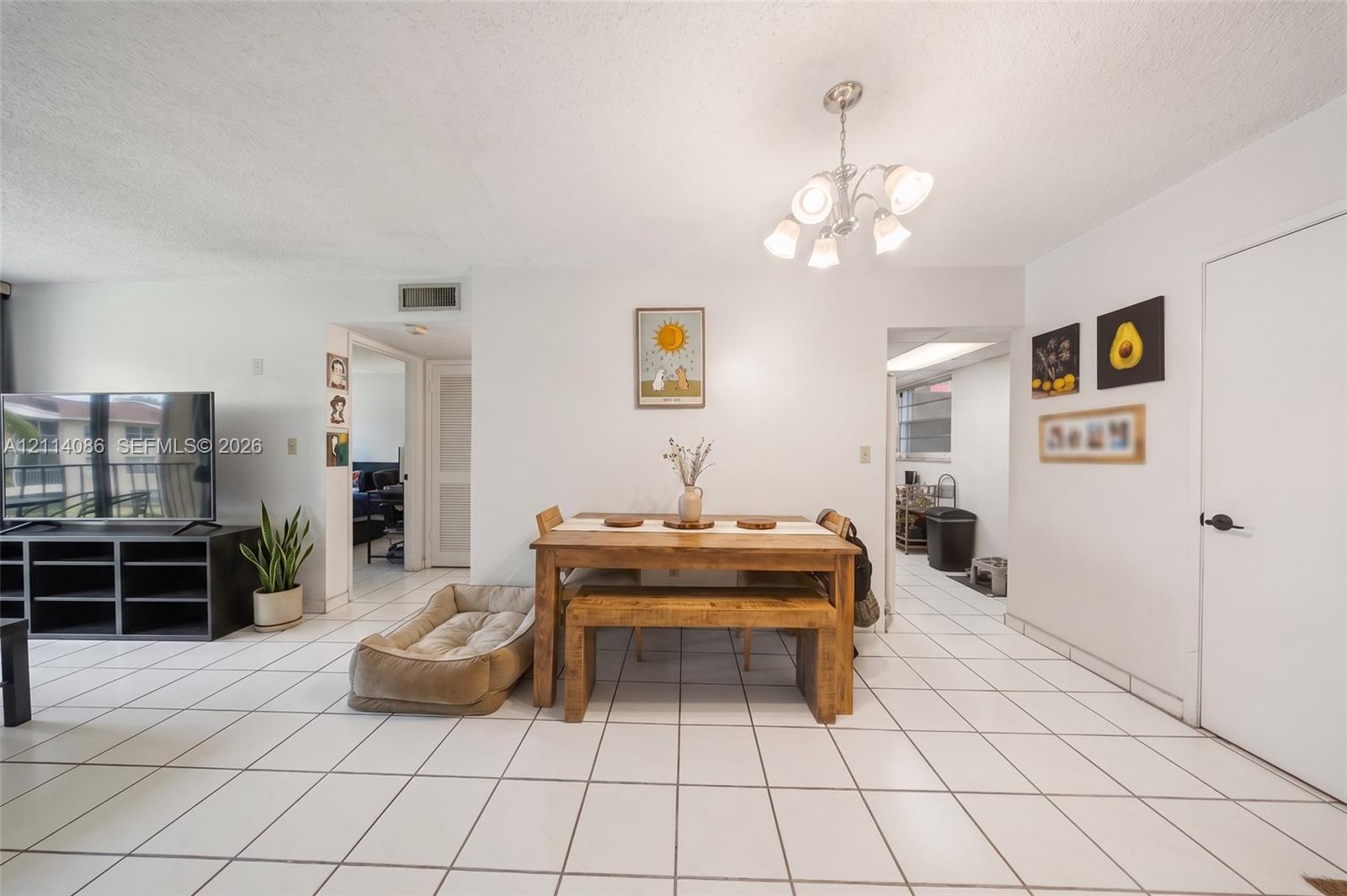 Open living space featuring light-colored tile flooring, neutral wall finishes, and a multi-arm chandelier