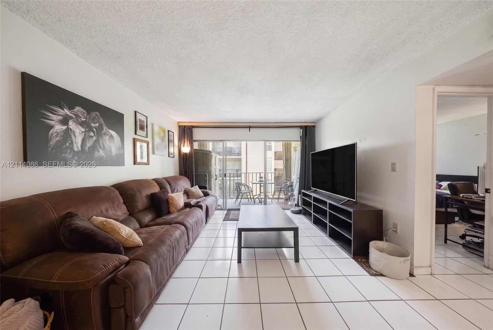 Living area featuring large-format ceramic tile flooring and sliding glass doors providing access to an exterior balcony