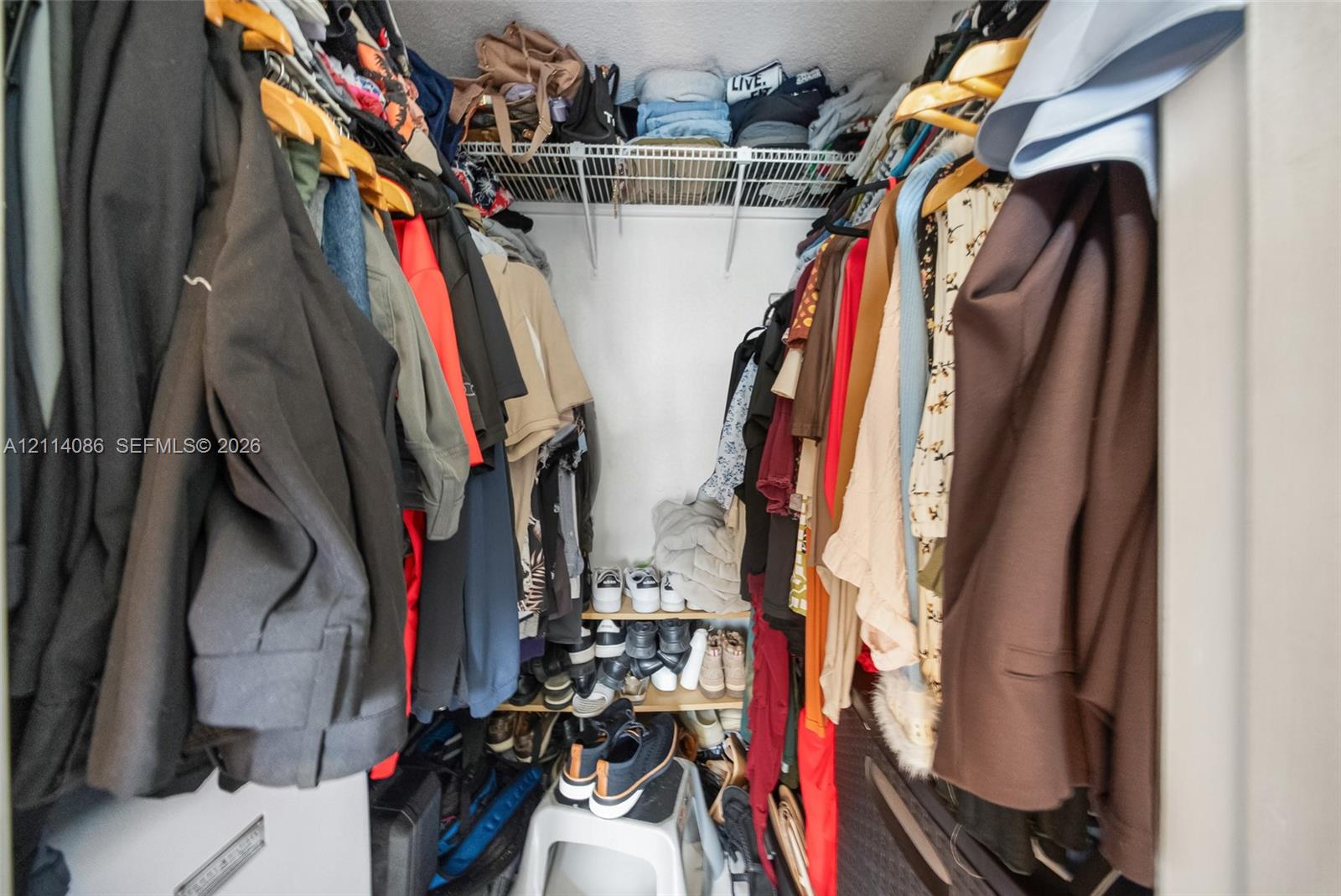 Storage closet featuring wire shelving and tiered built-in shelving