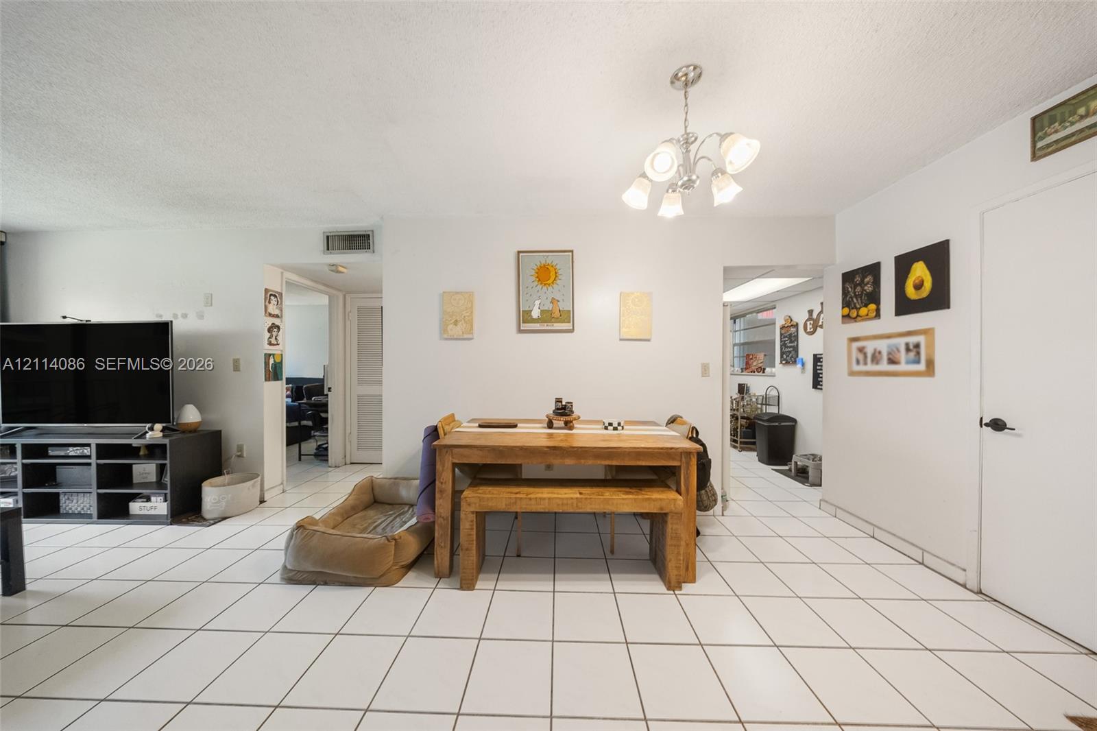 Open-concept area featuring white ceramic tile flooring and a multi-arm polished metal chandelier
