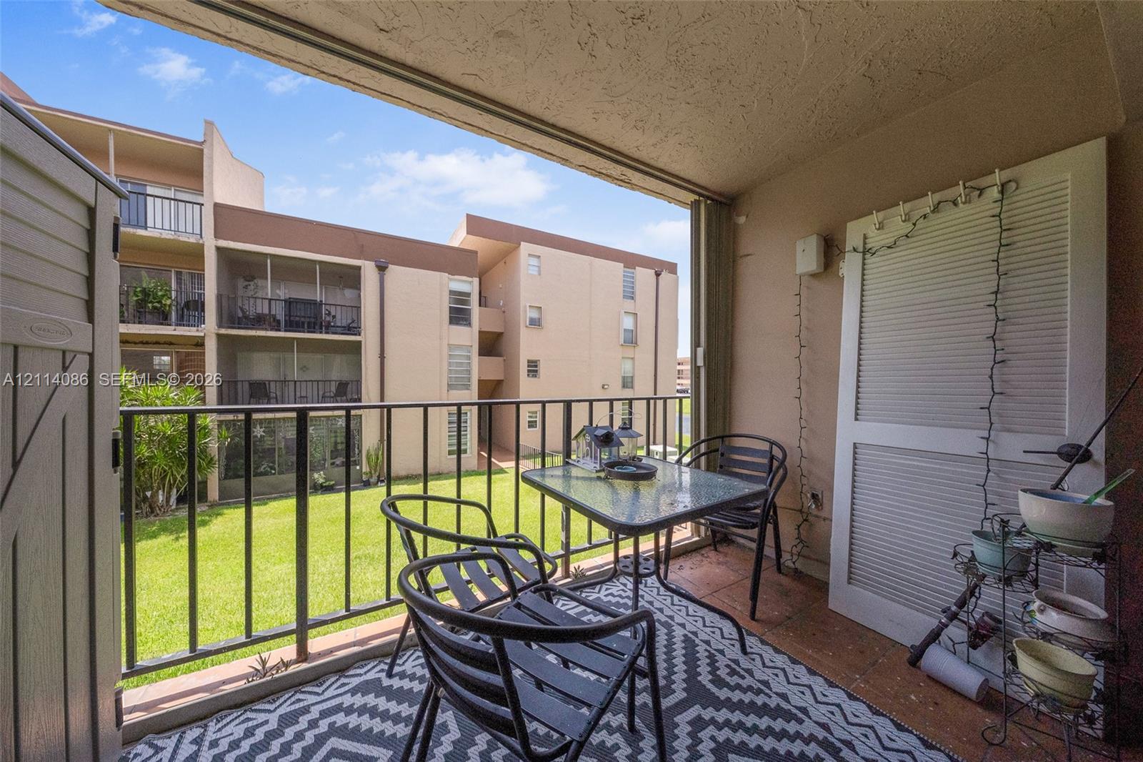 Covered balcony featuring tile flooring, metal railings, and integrated exterior storage
