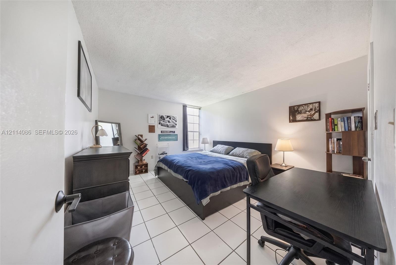 Interior room featuring white ceramic tile flooring and a vertical window with multi-pane grid detailing