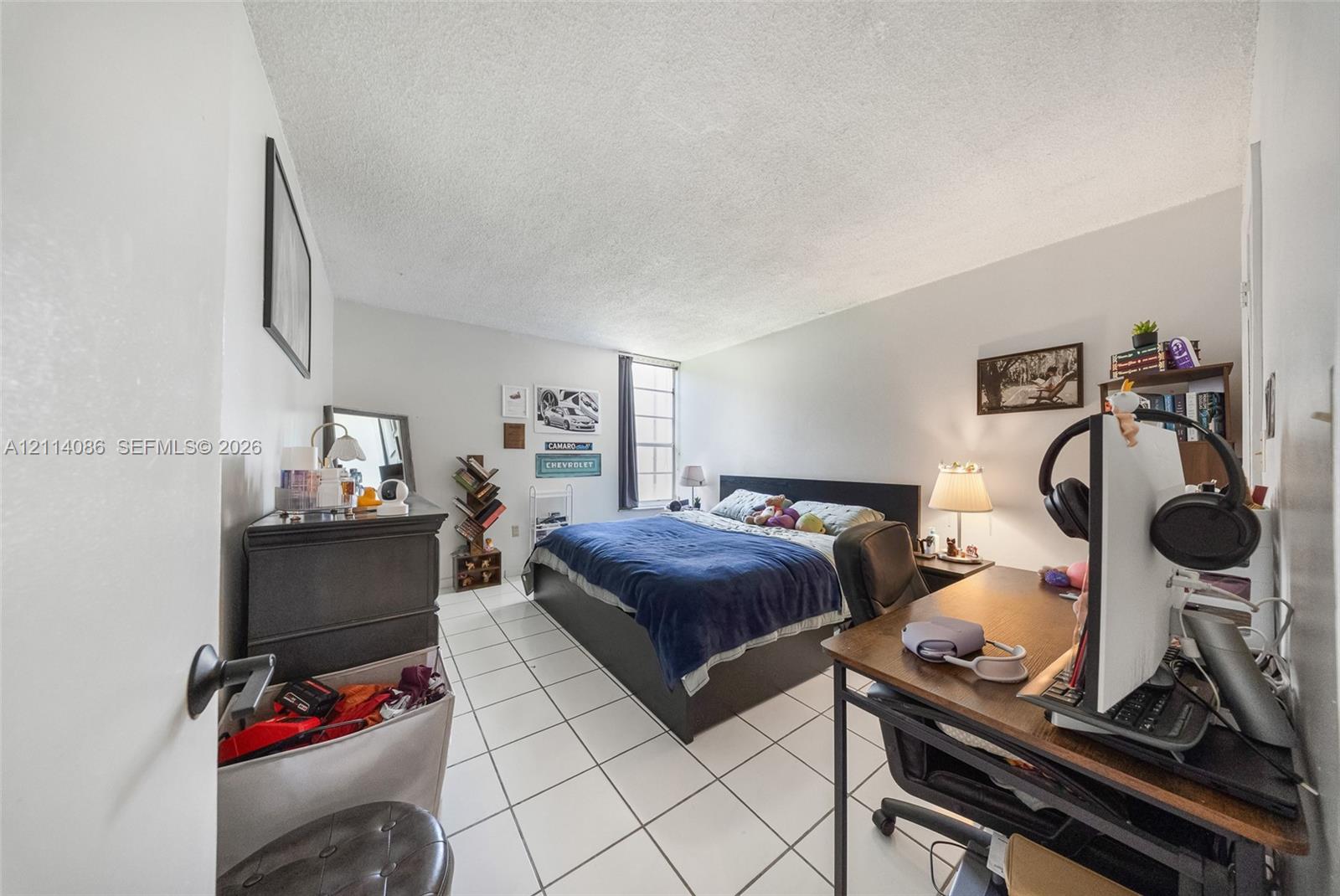 Room with white ceramic tile flooring, neutral wall paint, and a single-pane vertical window