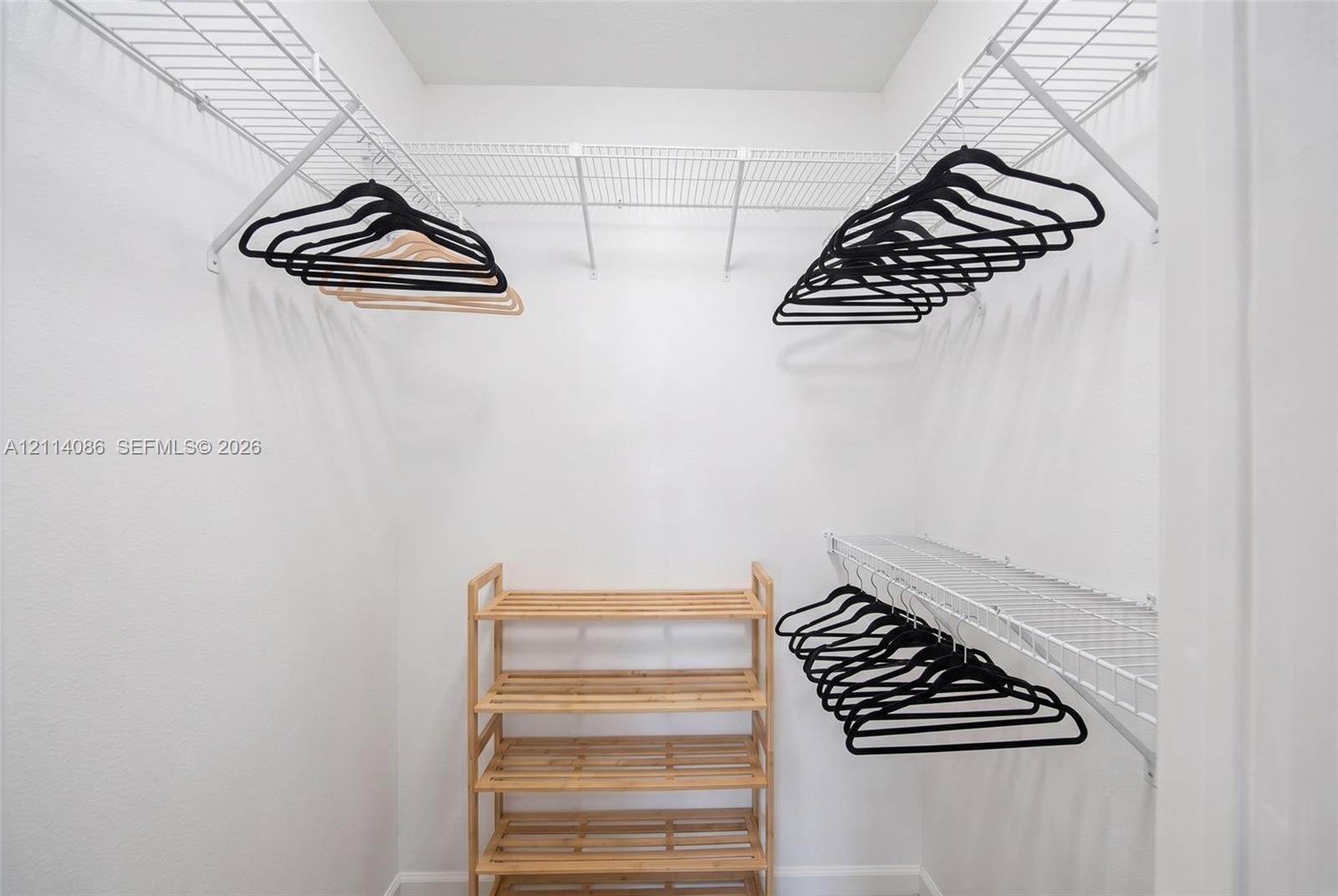 Walk-in closet featuring tiered white wire shelving