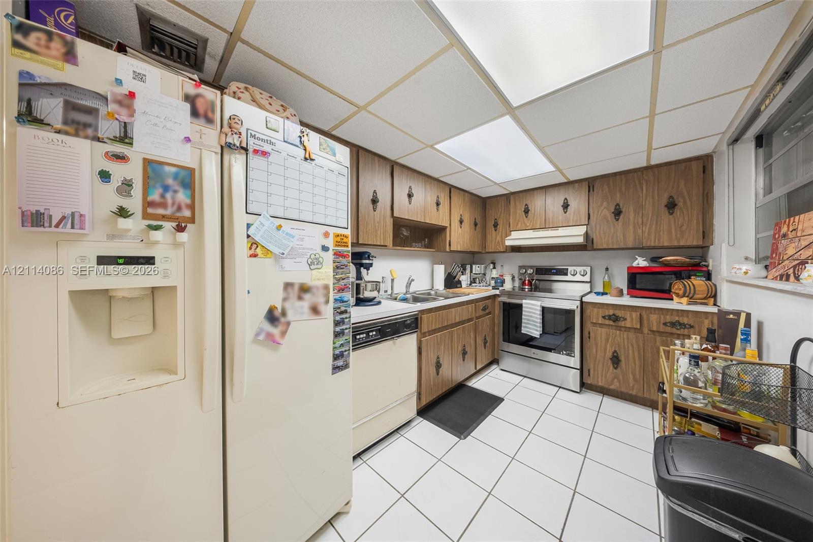 Kitchen featuring wood cabinetry, stainless steel range, integrated dishwasher, tiled flooring, and recessed ceiling lighting