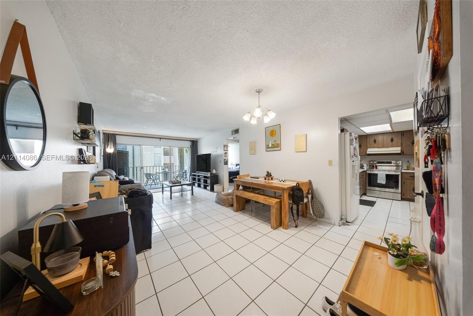 Open-concept floor plan featuring tile flooring, a multi-light chandelier, and a sliding glass door providing external access