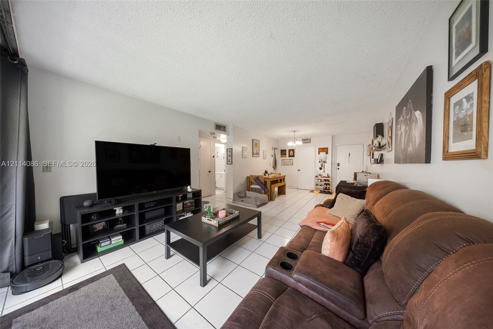 Living area featuring large format tile flooring, neutral wall paint, and overhead lighting fixtures