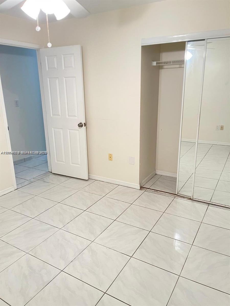 Ceramic tile flooring throughout, closet with mirrored sliding doors, and ceiling-mounted light fixture