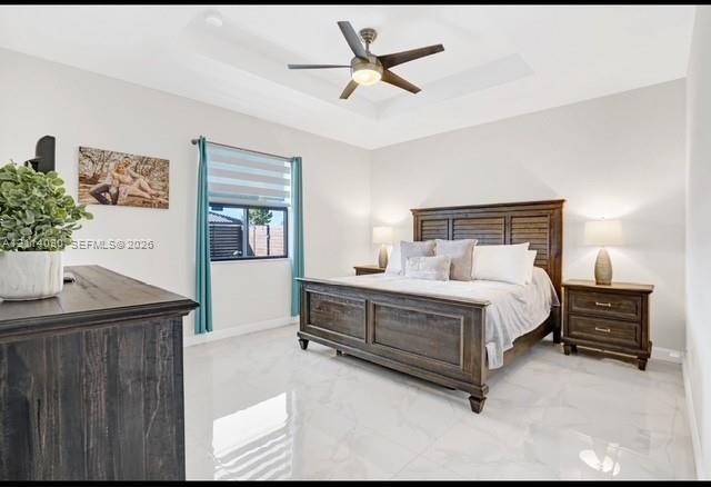 Tray ceiling featuring a central multi-blade ceiling fan with integrated lighting and polished, light-toned tile flooring