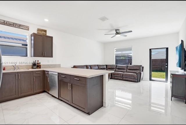 Kitchen featuring dark-finish cabinetry, neutral-toned countertops, stainless steel dishwasher, polished tile flooring, and a ceiling fan Kitchen featuring dark-finish cabinetry, neutral-toned countertops, stainless steel dishwasher, polished tile flooring, and a ceiling fan