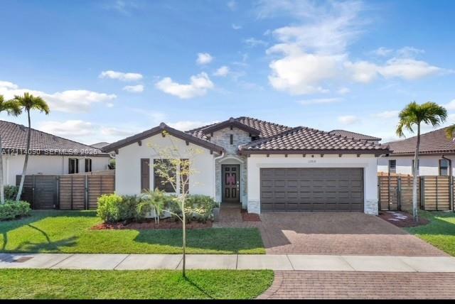 Single-story exterior featuring a tile roof, light-toned stucco finish, decorative stone accents, a brick-paver driveway, and a two-car garage Single-story exterior featuring a tile roof, light-toned stucco finish, decorative stone accents, a brick-paver driveway, and a two-car garage