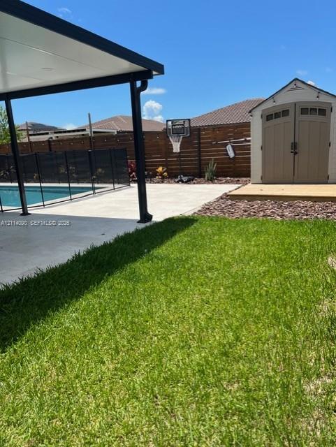 Backyard featuring a covered concrete patio, swimming pool with perimeter fencing, detached storage shed, and horizontal wood-slat privacy fencing Backyard featuring a covered concrete patio, swimming pool with perimeter fencing, detached storage shed, and horizontal wood-slat privacy fencing