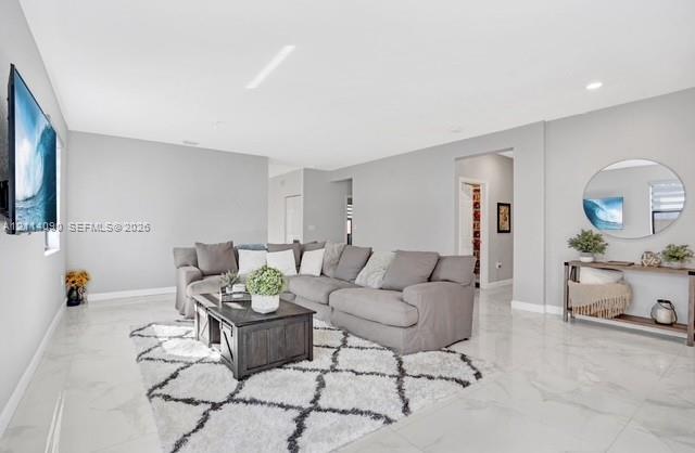 Open-concept living space featuring high-gloss tile flooring, recessed lighting, and neutral wall tones