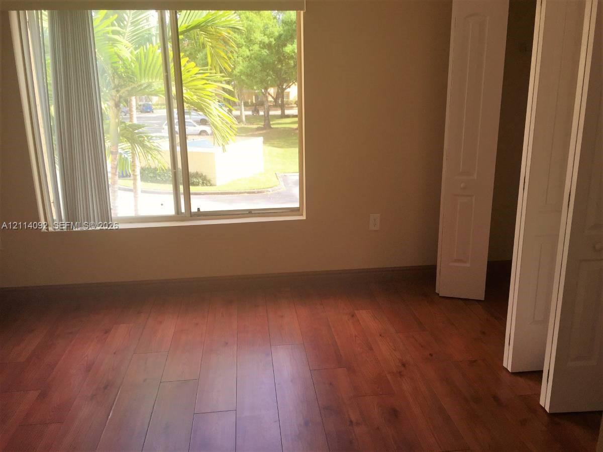 Wood-finish flooring, sliding glass window with neutral blinds, and dual-panel closet doors