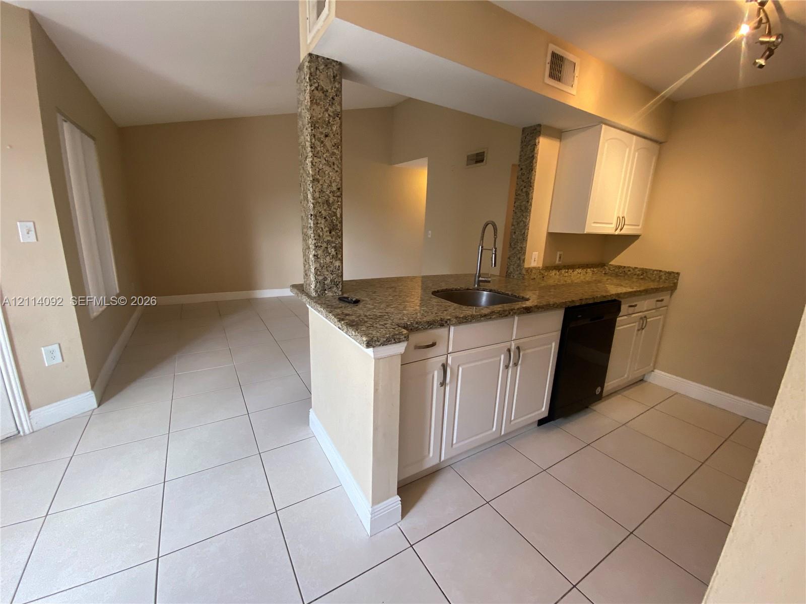Kitchen featuring white cabinetry, stone-surface countertops, tile flooring, a stainless steel sink with a high-arch faucet, and an integrated dishwasher