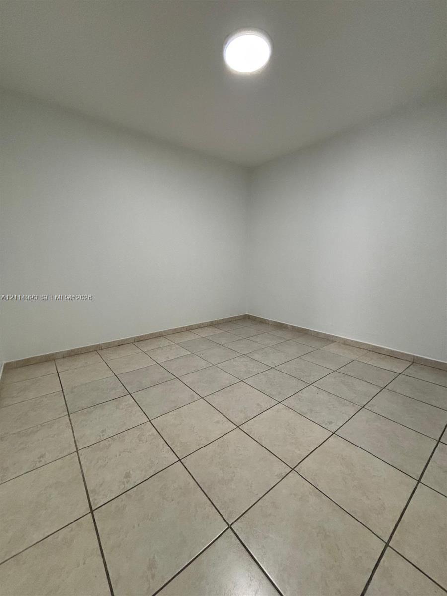 Interior space featuring neutral wall paint, ceramic floor tiling, and a flush-mount ceiling light fixture