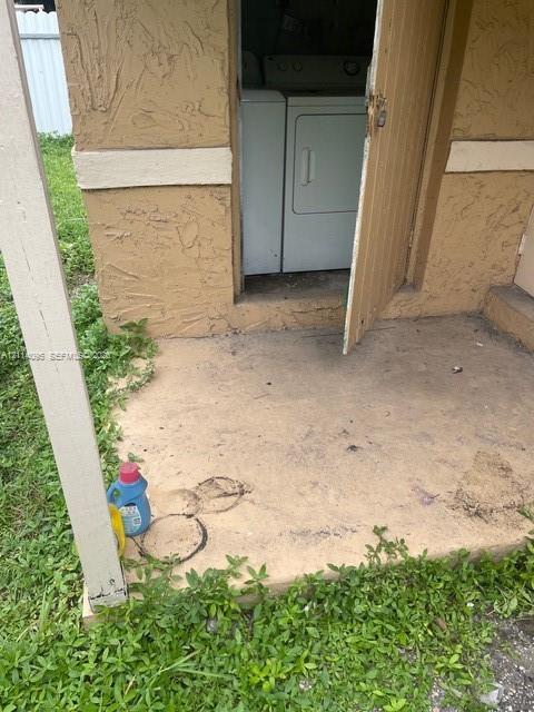 Exterior utility closet featuring a concrete landing, stucco siding, and dedicated appliance storage