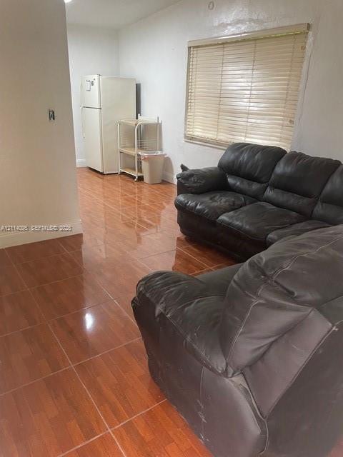 Glossy ceramic tile flooring featuring a wood-tone finish and horizontal window blinds